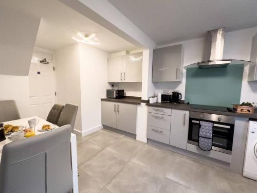 a kitchen with white cabinets and a table in it at Immaculate 5 Bedroom House in Rockingham