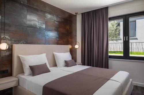 a bedroom with a large bed and a window at HADRIE LUXURY RESORT AND VILLAS ROVA b in Vantačići