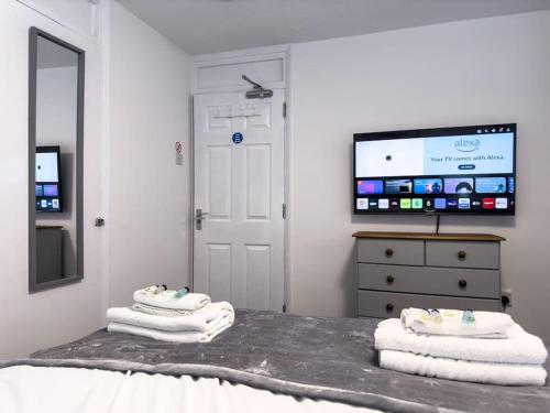 a bedroom with towels on a bed and a tv at Immaculate 5 Bedroom House in Rockingham