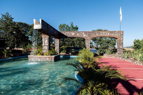 una piscina con una fuente y un puente en HOTEL & SPA LOS AGAVES, en Las Ánimas