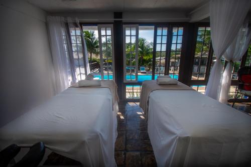 two beds in a room with a view of a pool at Pousada Lestada by Latitud Hoteles in Búzios