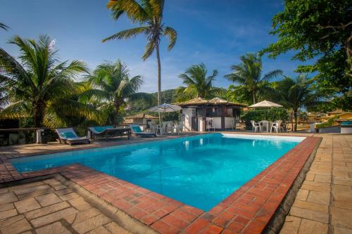 a swimming pool with blue water and palm trees at Pousada Lestada by Latitud Hoteles in Búzios