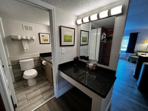 a bathroom with a sink and a toilet and a mirror at At Home Inn - Pensacola in Pensacola