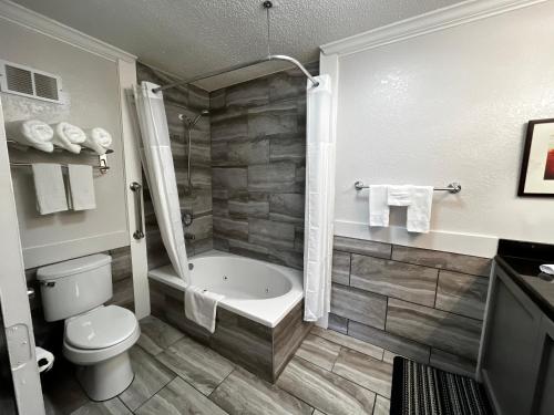 a bathroom with a tub and a toilet and a shower at At Home Inn - Pensacola in Pensacola