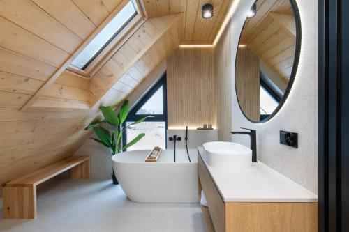 łazienka z dużą białą wanną i dużym lustrem w obiekcie Stylchyn Park Lakefront Lodges - Czorsztyn Exclusive with SPA w Kluszkowcach