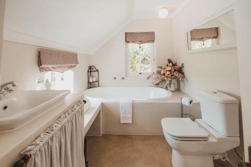 a bathroom with a tub and a toilet and a sink at Shades of Provence in Riebeek-Kasteel