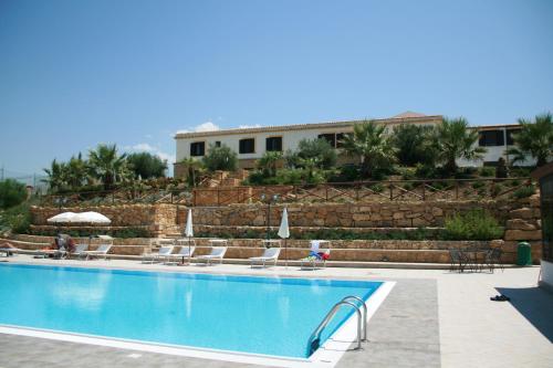 une piscine avec des chaises et un bâtiment en arrière-plan dans l'établissement Don Giovanni Hotel, à Sambuca di Sicilia