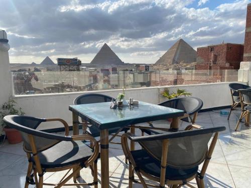a table and chairs on a roof with pyramids at Eagles Pyramids View in Cairo