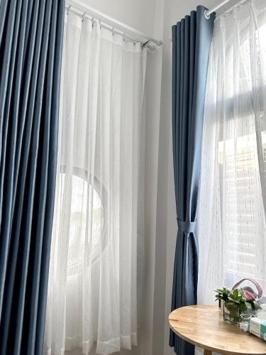 a room with blue and white curtains and a table at Aboli Homestay in Phan Thiet
