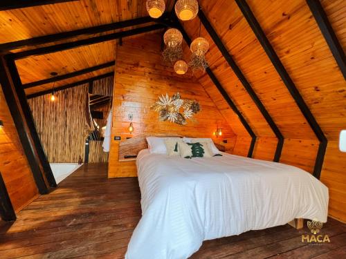a bedroom with a white bed in a wooden room at MACA GLAMPING in Calima