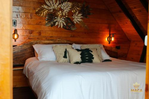 a bedroom with a white bed with wooden walls at MACA GLAMPING in Calima