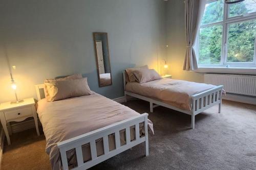 a bedroom with two beds and a mirror on the wall at Spacious Guest Flat near Roundhay Park in Roundhay