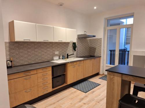 une cuisine avec des armoires en bois et un comptoir dans l'établissement Chambre FRIDA avec salle d'eau privée, à Agen