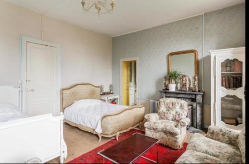 ein Schlafzimmer mit einem Bett, einem Stuhl und einem Spiegel in der Unterkunft Domaine du Parc et Château de Manou in Manou