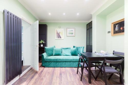 ein Wohnzimmer mit einem grünen Sofa und einem Tisch in der Unterkunft Stylish 2 Bedroom Flat, Sleep 6 & Garden London Zone 2 cls Central in London