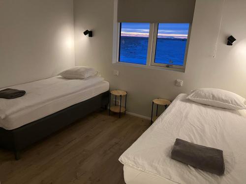 twee bedden in een kleine kamer met twee ramen bij Skógar Lodge in Hvolsvöllur