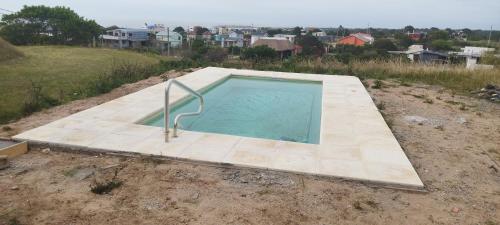 a swimming pool in the middle of a dirt field at Estrella de la viuda in Punta Del Diablo