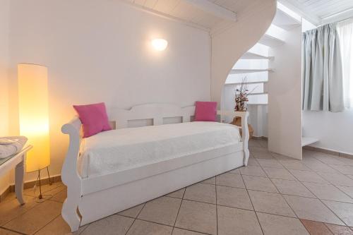 a bedroom with a white bed with pink pillows at Reverie Santorini Hotel in Firostefani