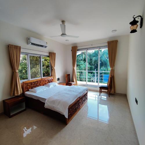 een slaapkamer met een bed en een groot raam bij Kasturi Villa - A home away from home in Mandve
