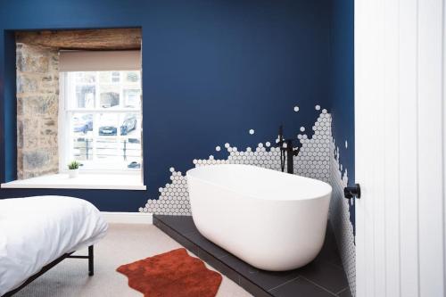 ein Schlafzimmer mit einer weißen Badewanne in einer blauen Wand in der Unterkunft The Bankers Quarters - Apt 2 in Chapel en le Frith
