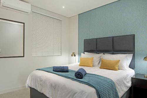 una camera da letto con un grande letto con due cuscini sopra di 601 at 2SIX2 Florida Road by HostAgents a Durban