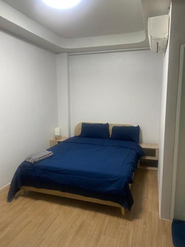 een slaapkamer met een bed met een blauwe sprei bij N place Huai Khwang in Bangkok