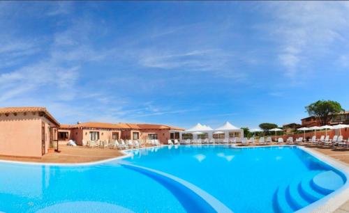 uma grande piscina num resort com cadeiras em Residence with swimming-pool in Vignola Mare em Vignola Mare