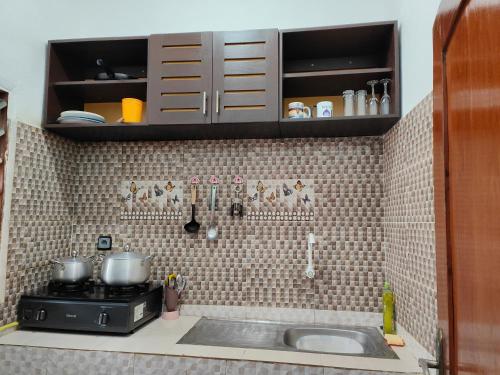 uma cozinha com um lavatório e uma parede em azulejo em Mawolè em Cotonou
