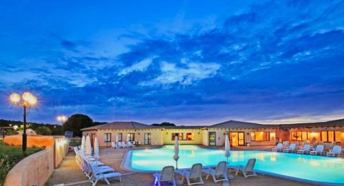 ein Resort mit einem Pool und Stühlen sowie einem Gebäude in der Unterkunft ISA-Residence with swimming-pool in Vignola Mare, apartments with air conditioning and private outdoor area in Vignola Mare