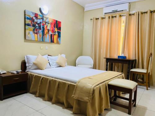 a bedroom with a bed with a table and a desk at Acropole Hotel in Cotonou