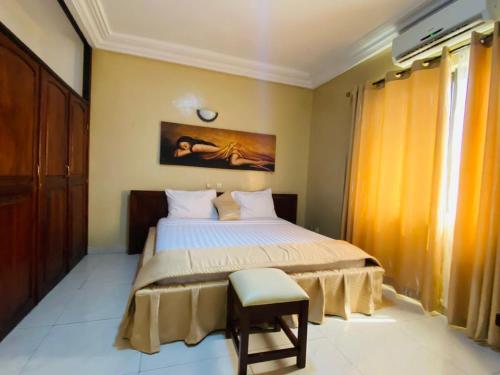 1 dormitorio con 1 cama y 1 silla en Acropole Hotel, en Cotonou