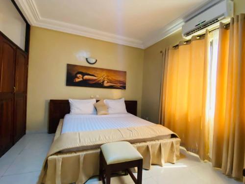1 dormitorio con 1 cama y 1 silla en Acropole Hotel, en Cotonou