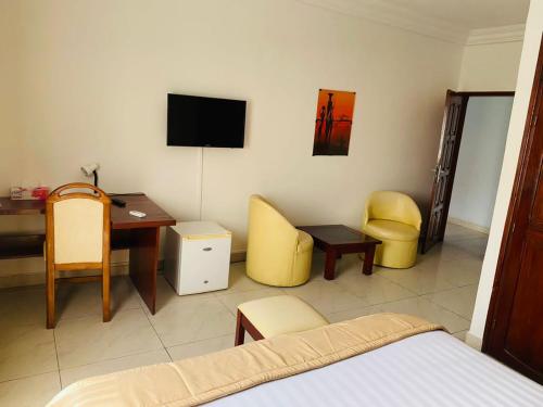 1 dormitorio con escritorio, 1 cama, mesa y sillas en Acropole Hotel en Cotonú