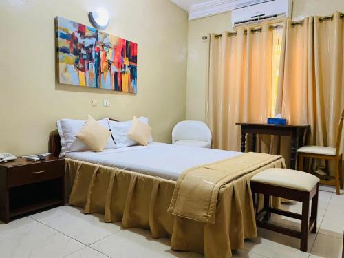 1 dormitorio con 1 cama con mesa y sillas en Acropole Hotel, en Cotonou