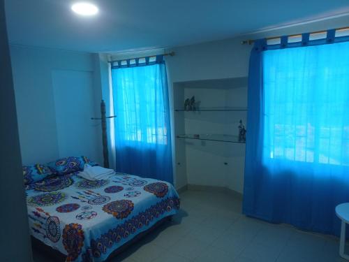 een slaapkamer met een bed en blauwe gordijnen bij Casa Blanca Ciudad Jardín in Barranquilla