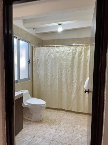 a bathroom with a toilet and a shower curtain at Hotel Bajo el Volcan in Cuernavaca