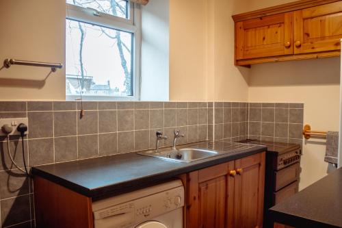 eine Küche mit einem Waschbecken und einem Fenster in der Unterkunft Rustic Cottage in Heart of Town in Otley