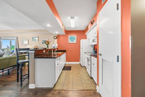 cocina con paredes de color naranja, armarios blancos y mesa en Oceanfront Get Away, en Myrtle Beach