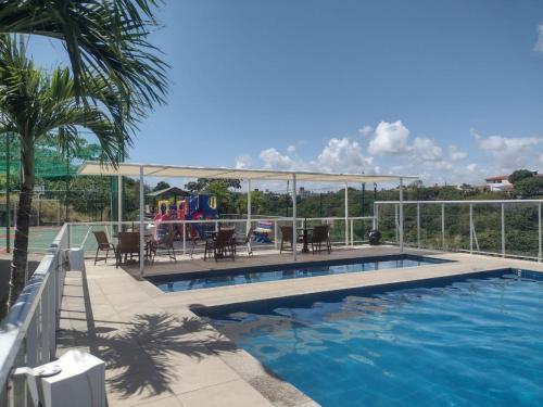 einen Pool mit Stühlen und einen Spielplatz in der Unterkunft Residencial Jardim da costa in João Pessoa