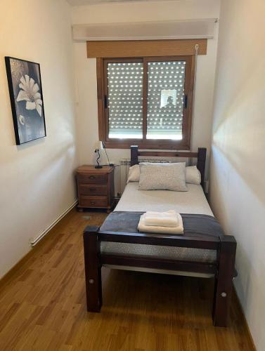 a small bedroom with a bed with a window at Pension Matias Rooms in Sarria