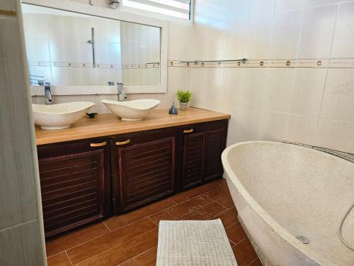 VILLA VALIHA في Koungou: حمام به مغسلتين وحوض استحمام ومرآة
