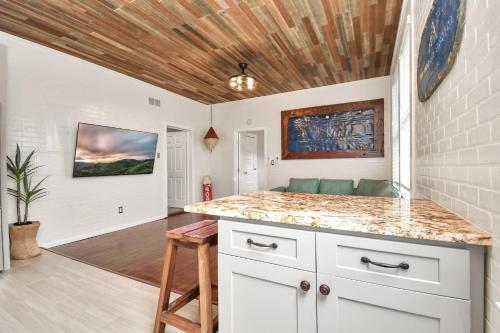 a kitchen with white cabinets and a wooden ceiling at Nautical Loft with Outdoor Kitchen & Beach Access in Galveston