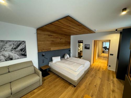 1 dormitorio con 1 cama y 1 sofá en Hotel Kärntnerhof en Heiligenblut
