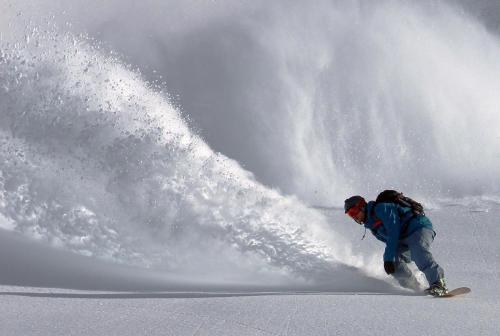 a man riding a snowboard down a snow covered slope at Union Cove in Salt Lake with Secluded Privacy in Midvale
