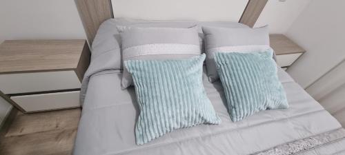 Cama con sábanas blancas y almohadas verdes en Casa Barbeiro, en Pombal