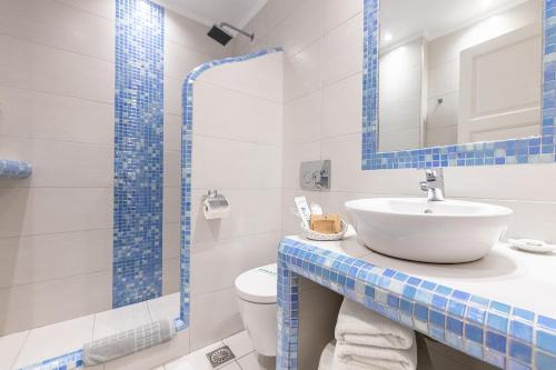 a blue and white bathroom with a sink and a toilet at Reverie Santorini Hotel in Firostefani