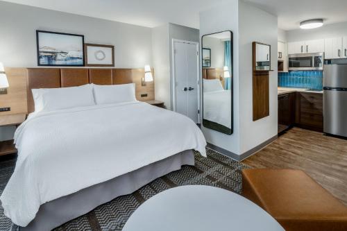 a bedroom with a large white bed and a kitchen at Staybridge Suites Denver - Cherry Creek, an IHG Hotel in Denver
