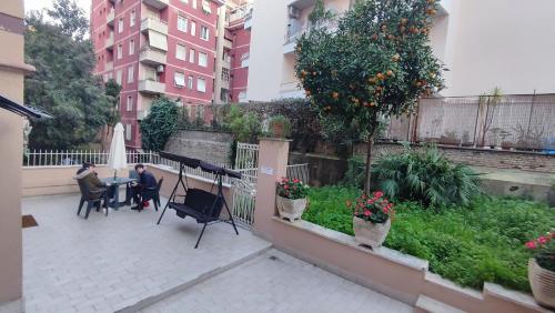 羅馬的住宿－VATICAN GREEN GARDEN，两个人坐在庭院里,坐在桌子上,庭院里有一棵橘子树