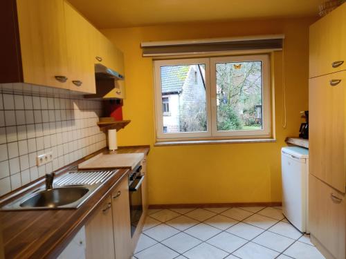 cocina con paredes amarillas, lavabo y ventana en Ferienhaus Route 5, en Elmstein