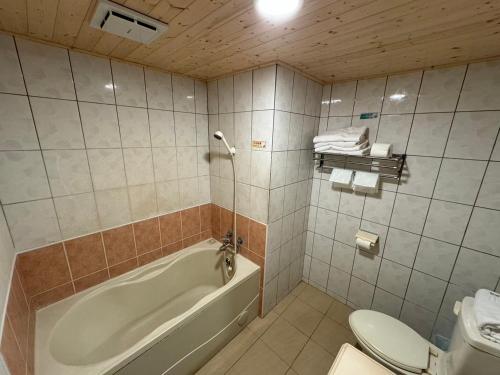Yawan Hotel في Wenquan: حمام مع حوض استحمام ومرحاض